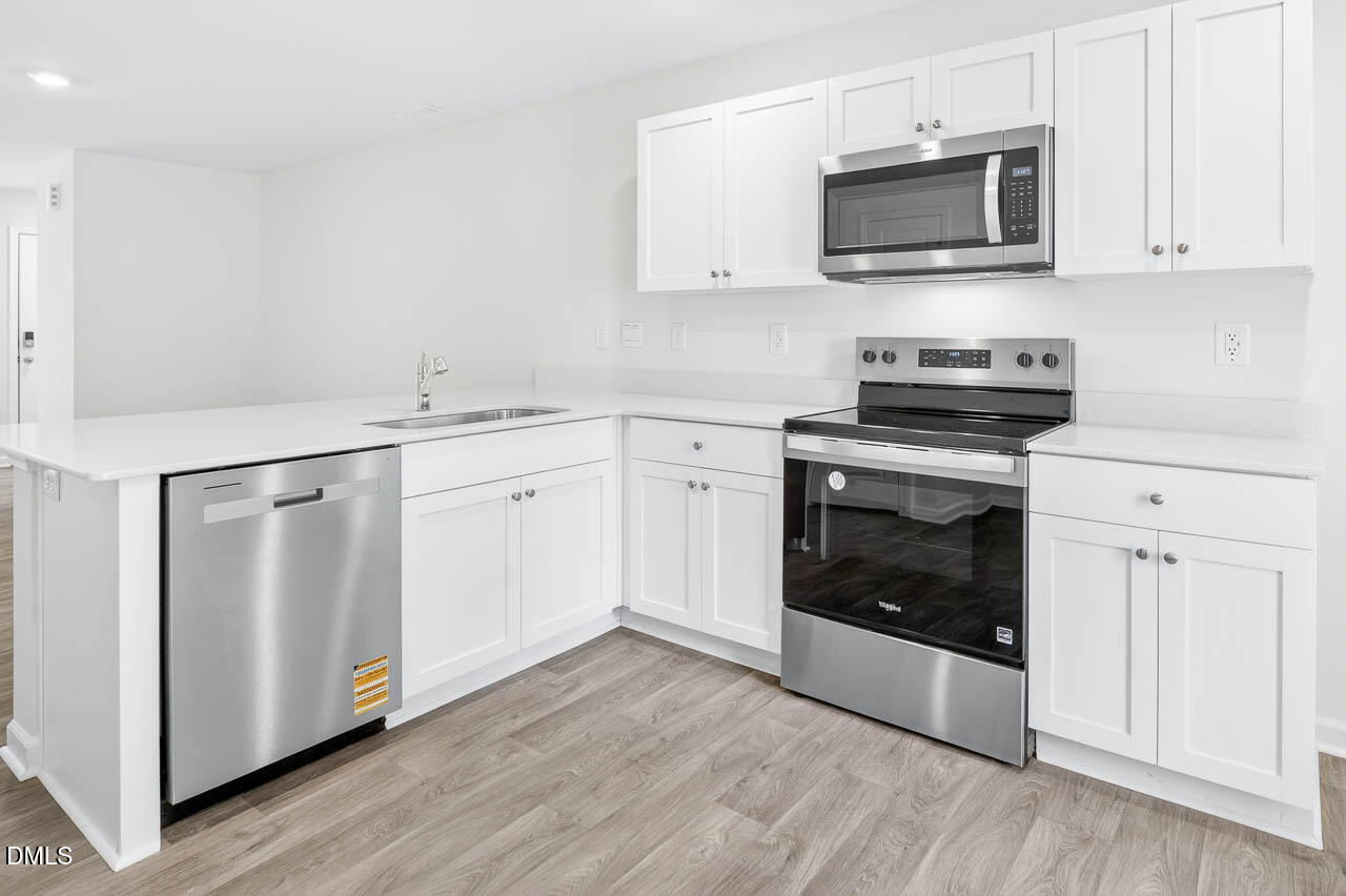 8535 Beckett Chase Way Raleigh, NC 27616 - Photo 6 of 33 a kitchen with cabinets stainless steel appliances a sink and wooden floor