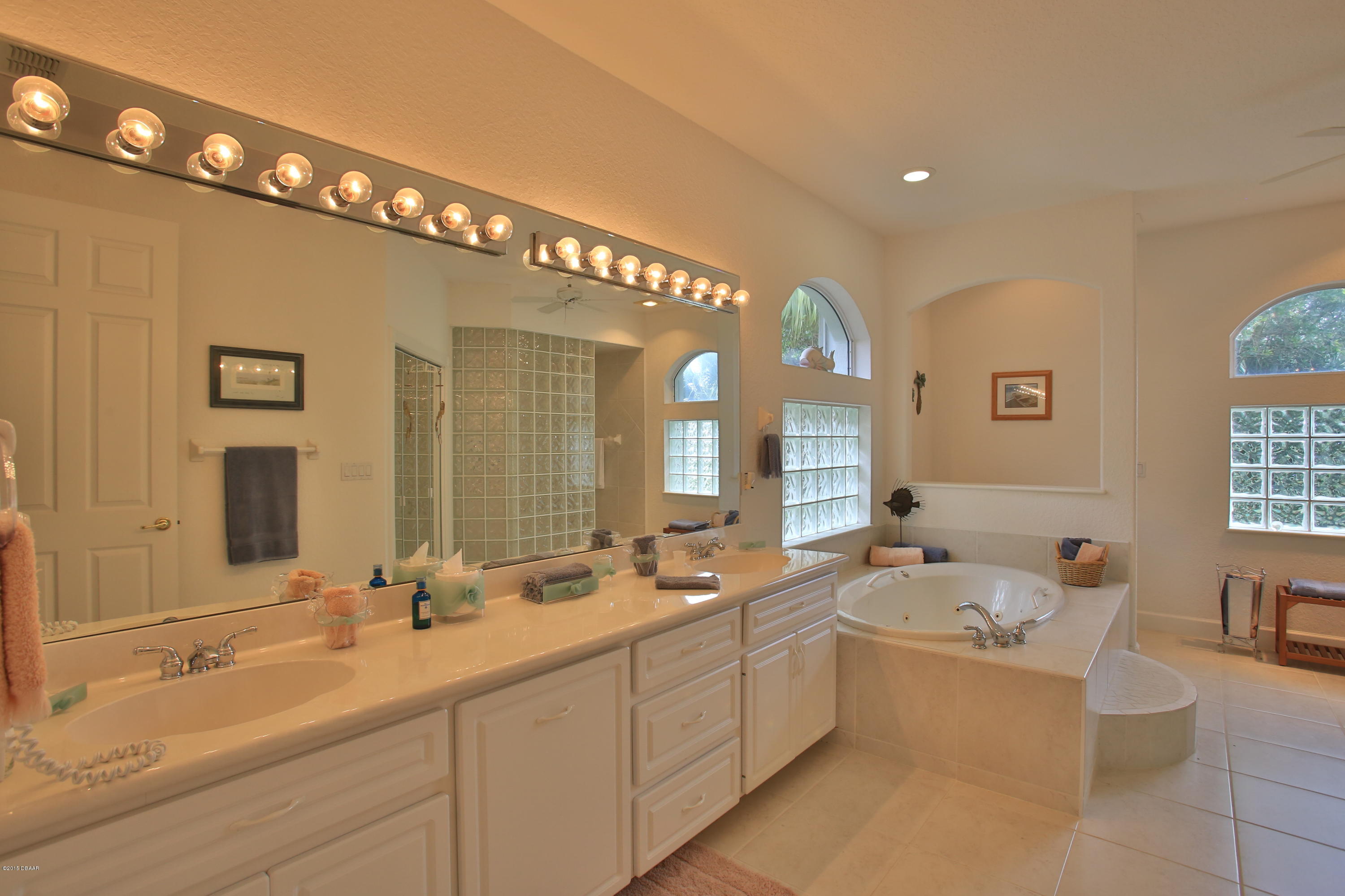 35 Inlet Point Boulevard Ponce Inlet, FL 32127 - Photo 14 of 34 a spacious bathroom with a double vanity sink a mirror a bathtub and next to a window