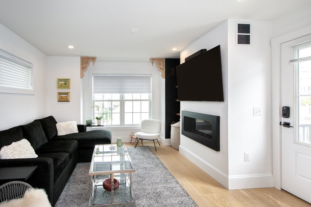 83 Glades Road Scituate, MA 02066 - Photo 7 of 37 a living room with furniture a flat screen tv and a fireplace