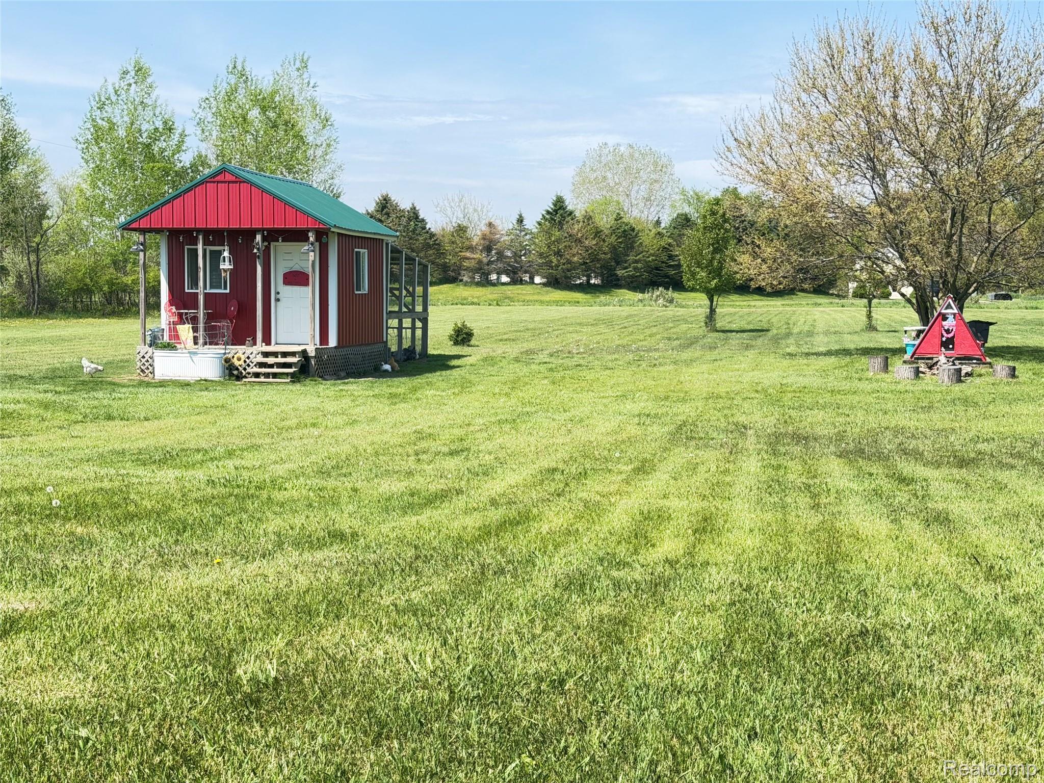 6860 Grand River Road Bancroft, MI 48414 - Photo 28 of 31 View of grassy yard featuring an outdoor structure, covered porch, and view of wooded area