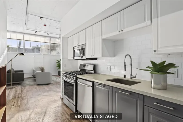 a kitchen with stainless steel appliances a sink a stove and white cabinets