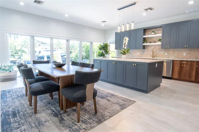 a large kitchen with kitchen island a sink a stove a refrigerator and a dining table with wooden floor