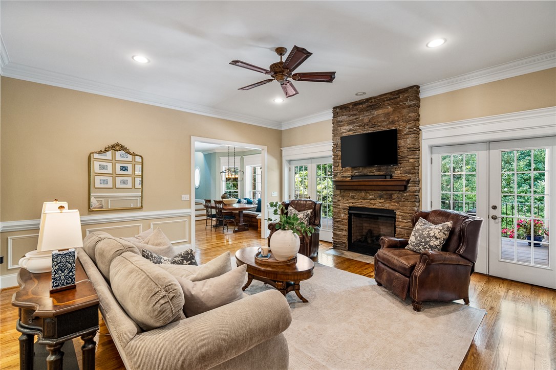 200 Graylyn Drive Anderson, SC 29621 - Photo 7 of 48 A comforting living room, adorned with a stone fireplace, transitions seamlessly to outdoor spaces through elegant French doors.