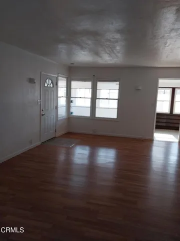 a view of an empty room with wooden floor and window