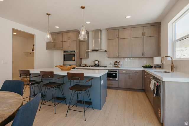 5902 Canyon Rim Road, Unit 620 Lehi, UT 84048 - Photo 11 of 78 Modern kitchen featuring a central island with countertop seating, light wood-finish flooring, light gray cabinetry, and stainless steel appliances