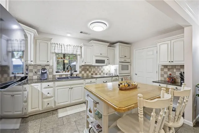 a kitchen with stainless steel appliances granite countertop a stove refrigerator dining table and chairs