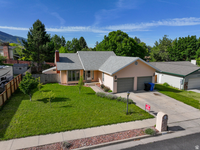 1218 East 100 South Logan, UT 84321 - Photo 2 of 23 Ranch-style residence featuring a pale peach exterior, light gray shingle roof, and an attached two-car garage