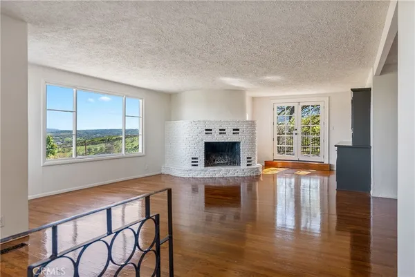 an empty room with fireplace wooden floor and windows