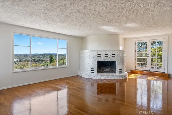 a view of an empty room with a window and kitchen view