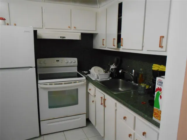 a kitchen with white cabinets and sink