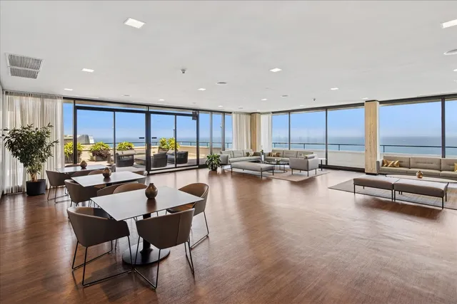 a dining room with furniture water view and a floor to ceiling window