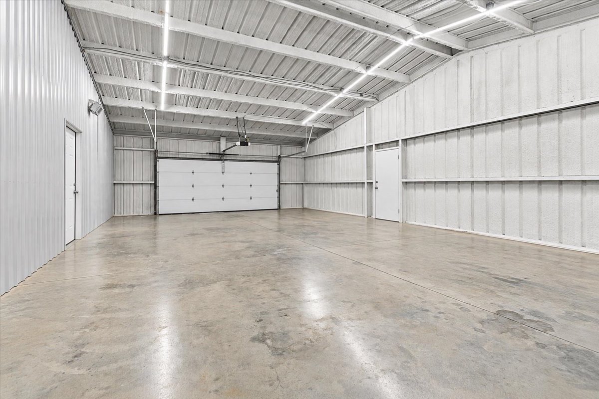 12 Hoot Loop Cartwright, OK 74731 - Photo 22 of 35 Spacious interior featuring a concrete floor, corrugated metal walls, and a large roll-up door