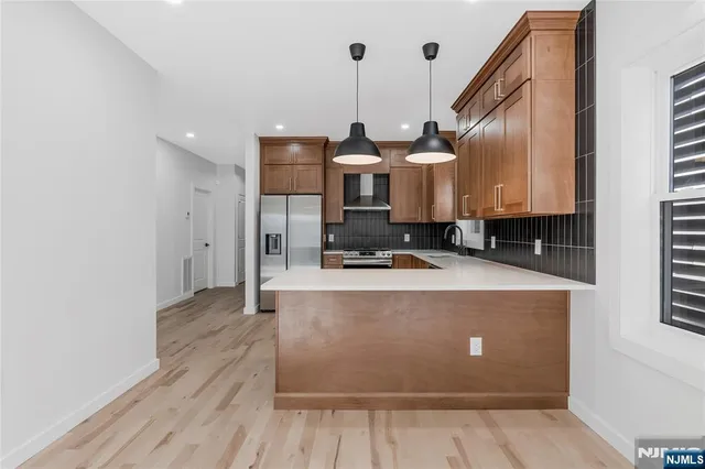 a view of a kitchen with kitchen island stainless steel appliances wooden floor sink and wooden floor