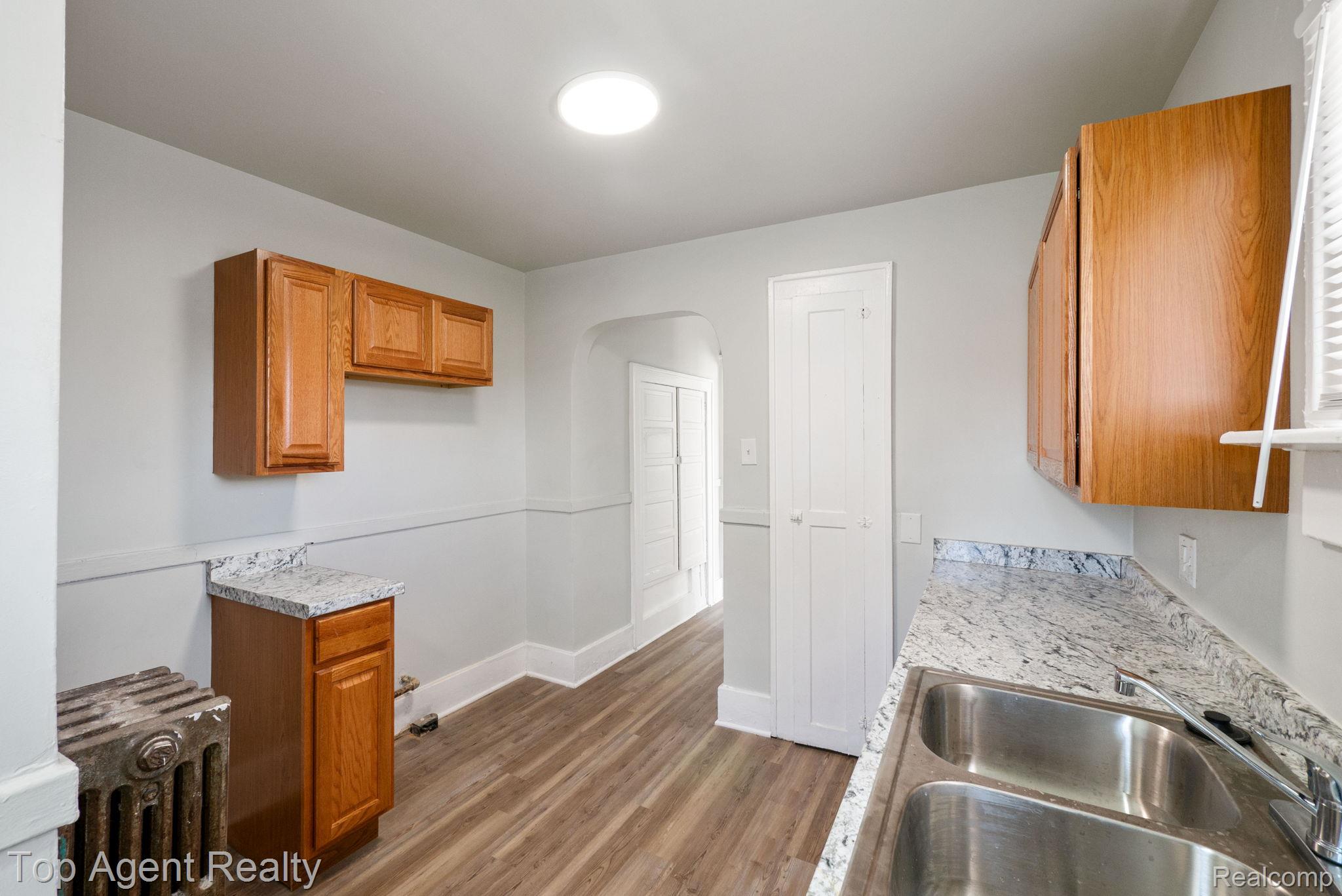 19217 Reno Street Detroit, MI 48205 - Photo 26 of 45 Kitchen featuring wood-finish flooring, light wood cabinetry, granite-style countertops, and a double basin stainless steel sink