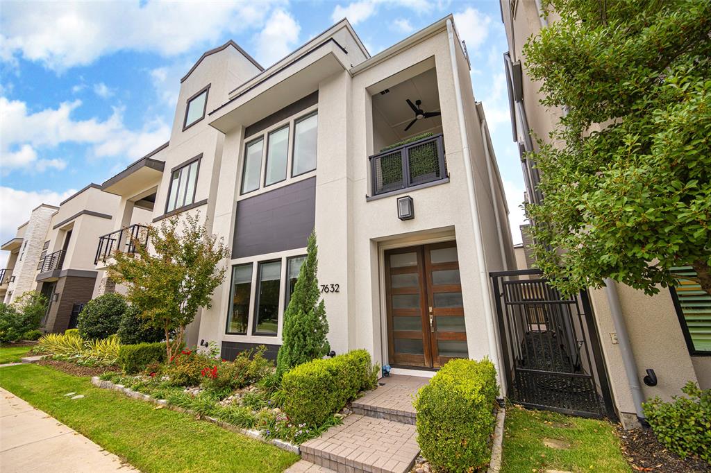 a view of a house with brick walls plants and large tree