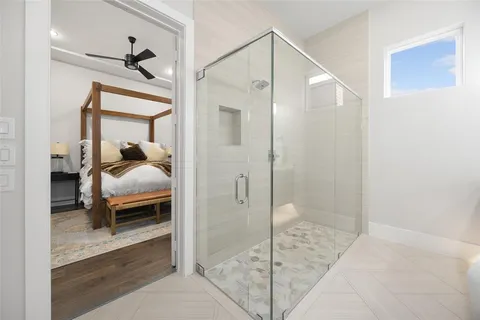 a bedroom with a bed and a glass door shower