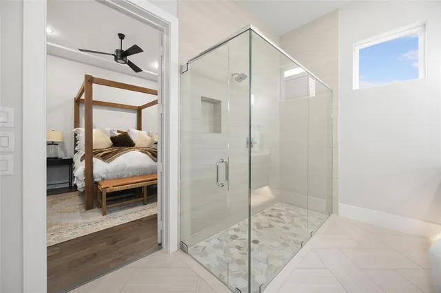 a bedroom with a bed and a glass door shower