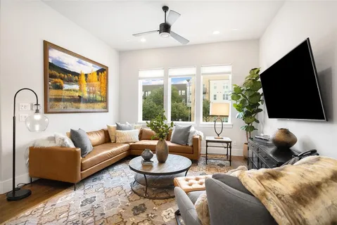 a living room with furniture a flat screen tv and a floor to ceiling window
