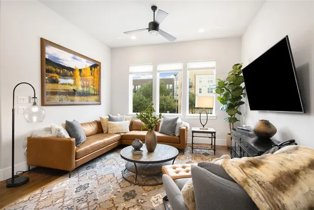 a living room with furniture a flat screen tv and a floor to ceiling window