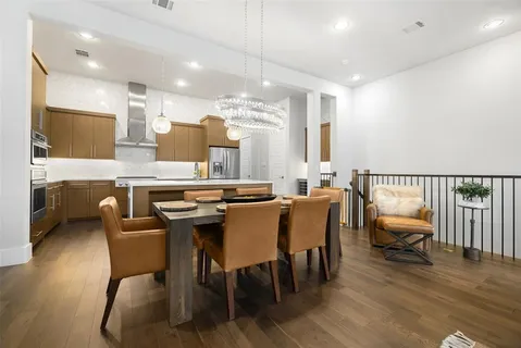 a dining hall with stainless steel appliances kitchen island granite countertop a dining table chairs and a kitchen view