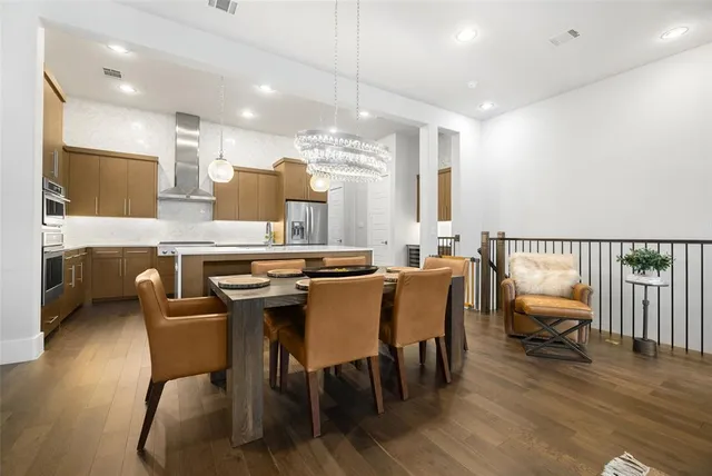 a dining hall with stainless steel appliances kitchen island granite countertop a dining table chairs and a kitchen view