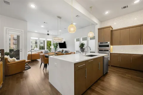 a large kitchen with kitchen island a large counter top a sink stainless steel appliances and cabinets