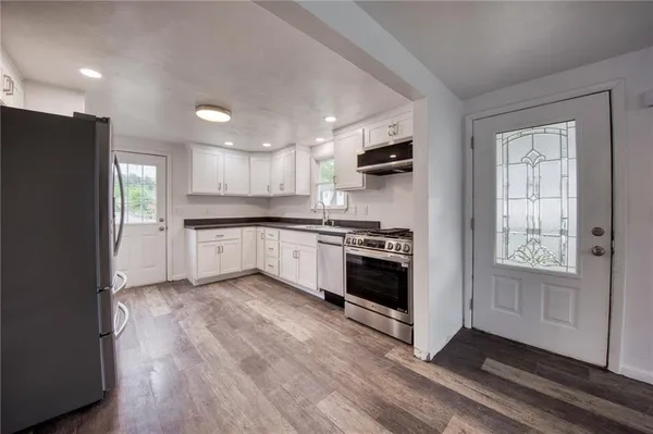 a kitchen with granite countertop a refrigerator stove and sink