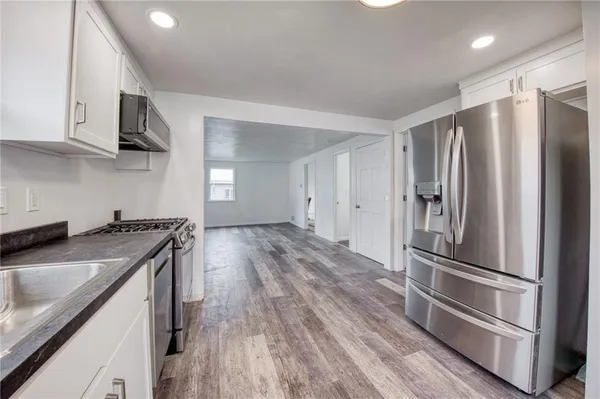 a kitchen with granite countertop a refrigerator stove and sink
