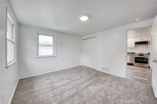 an empty room with windows and a kitchen
