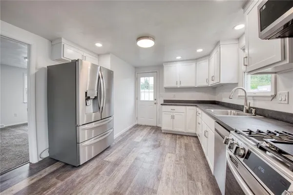 a kitchen with granite countertop a refrigerator stove and wooden floor