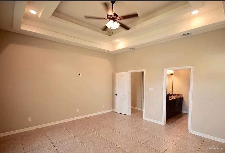 1919 West Ventura Drive Pharr, TX 78577 - Photo 12 of 20 Unfurnished bedroom featuring a tray ceiling, light tile patterned floors, recessed lighting, connected bathroom, and a ceiling fan