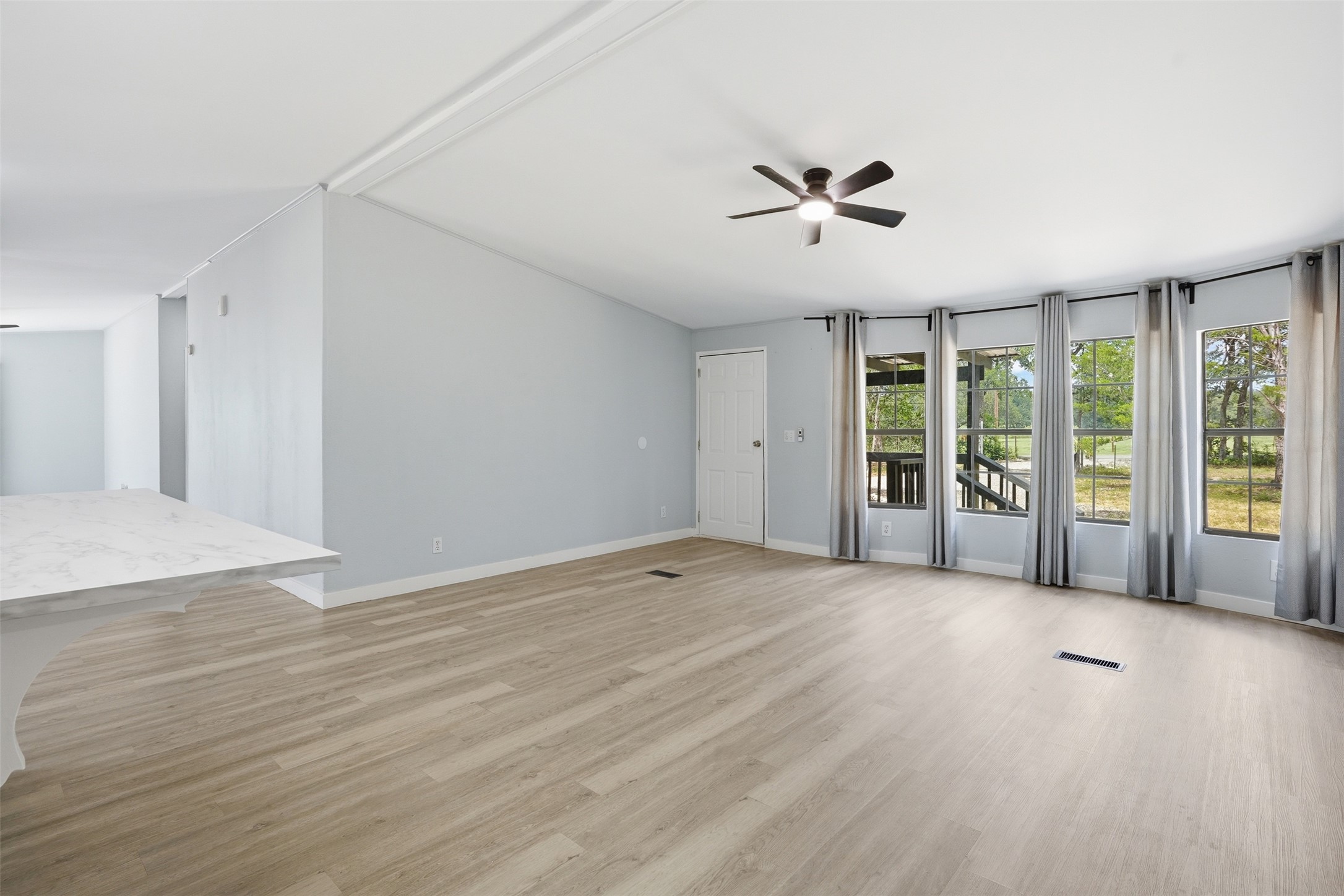 154 Antioch Road Smithville, TX 78957 - Photo 2 of 32 A well-lit living area with pale wood flooring and a view of the outdoors through multiple windows.