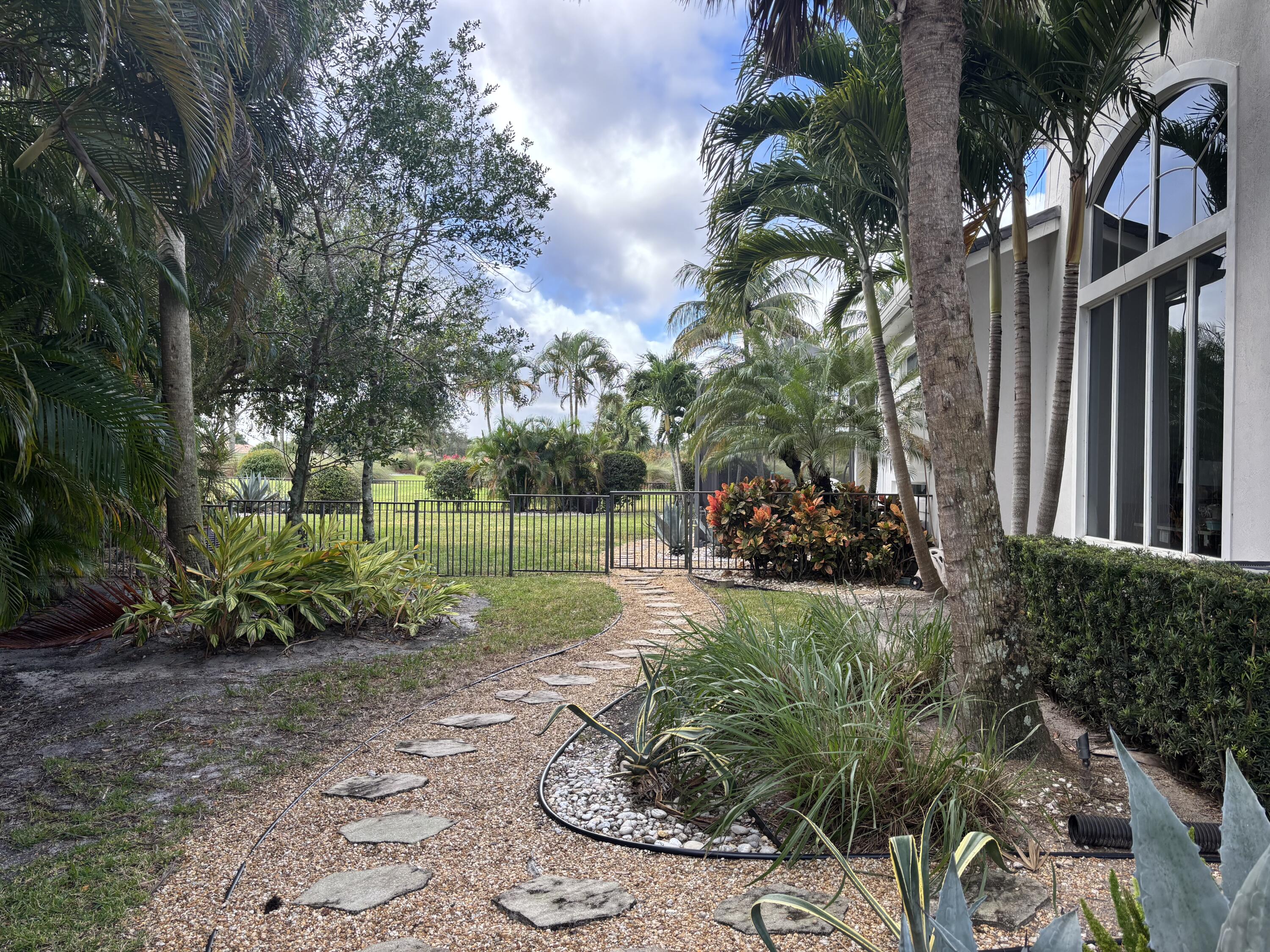 182 Rosalia Court Jupiter, FL 33478 - Photo 17 of 32 a view of a backyard with potted plants and large trees