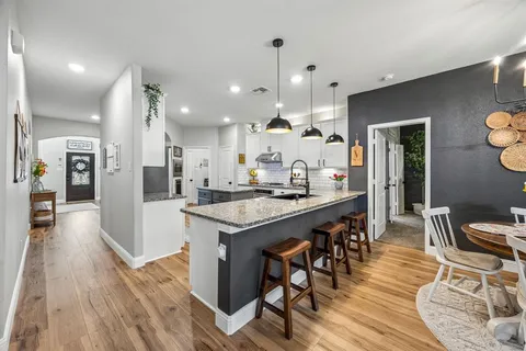 a kitchen with stainless steel appliances kitchen island granite countertop a table chairs and a wooden floor