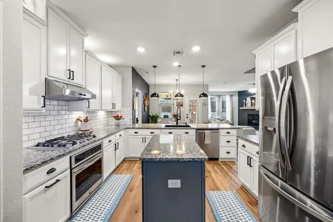 a large kitchen with stainless steel appliances granite countertop a stove refrigerator and a sink