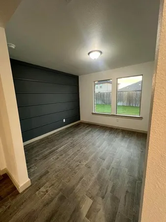 an empty room with wooden floor and windows