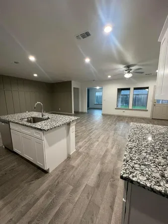 a large white kitchen with kitchen island granite countertop a large counter top and stainless steel appliances