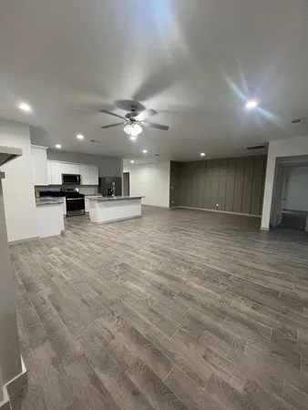 a view of an empty room with kitchen and a window