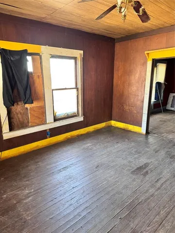 a view of empty room with wooden floor and fan