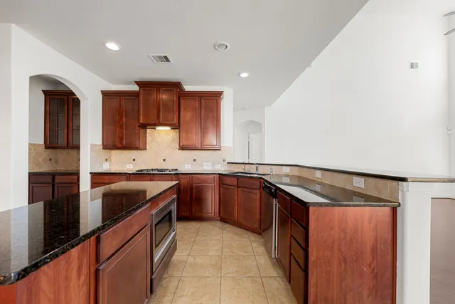 a large kitchen with granite countertop a sink and dishwasher a stove top oven with wooden floor