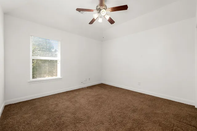 an empty room with a window and a fan