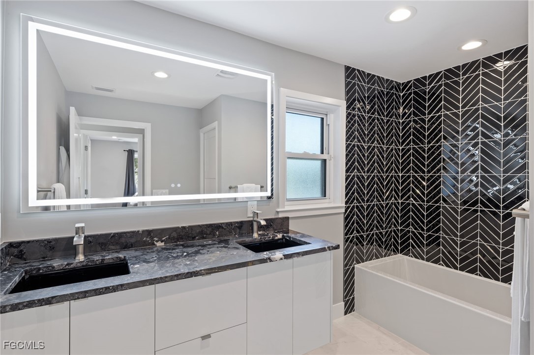 432 Seaworthy Road North Fort Myers, FL 33903 - Photo 17 of 28 a bathroom with a granite countertop bathtub sink vanity and mirror
