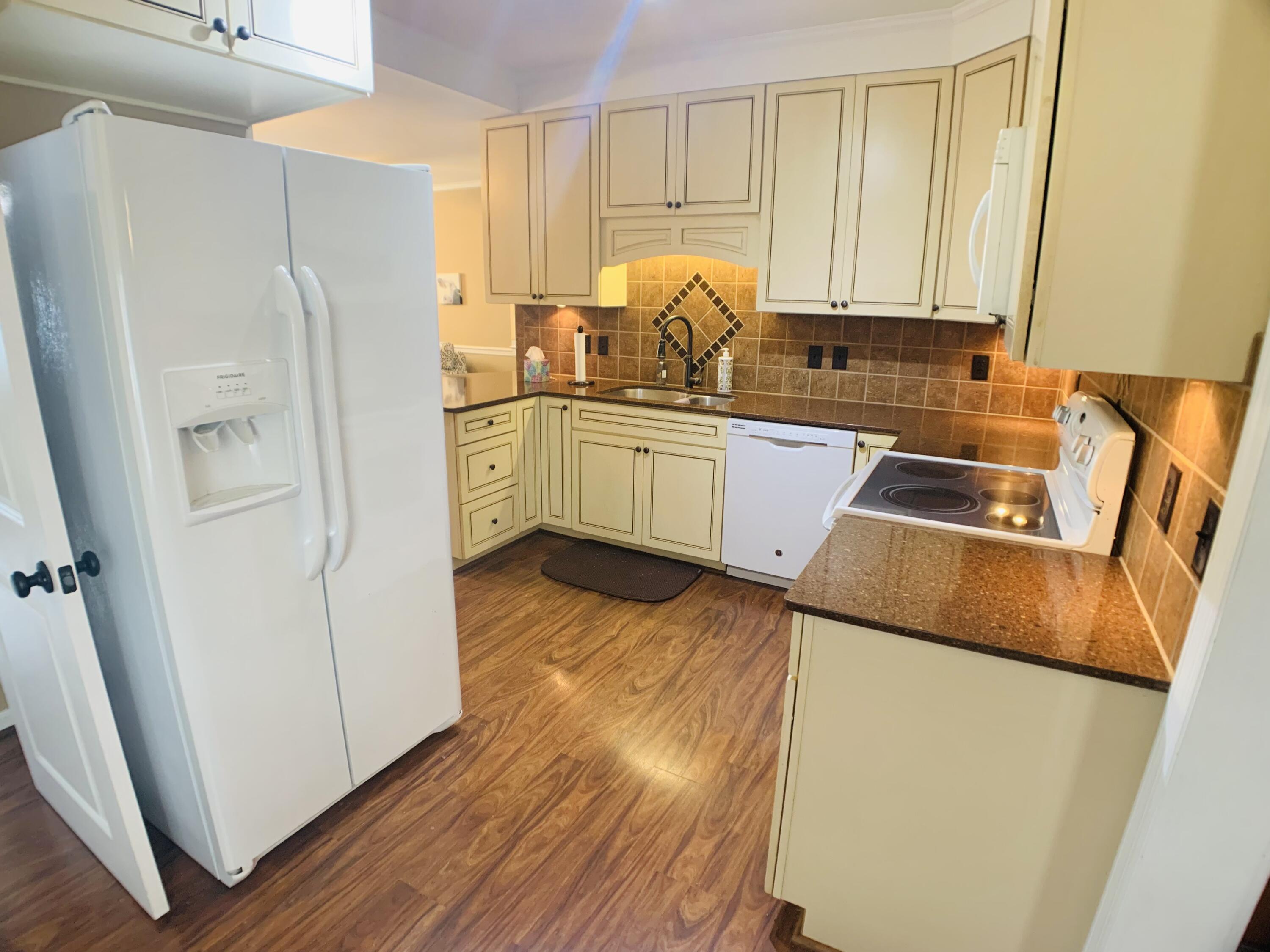 709 McCormick Boulevard Clifton Forge, VA 24422 - Photo 21 of 74 a kitchen with a refrigerator a stove a sink and white cabinets with wooden floor
