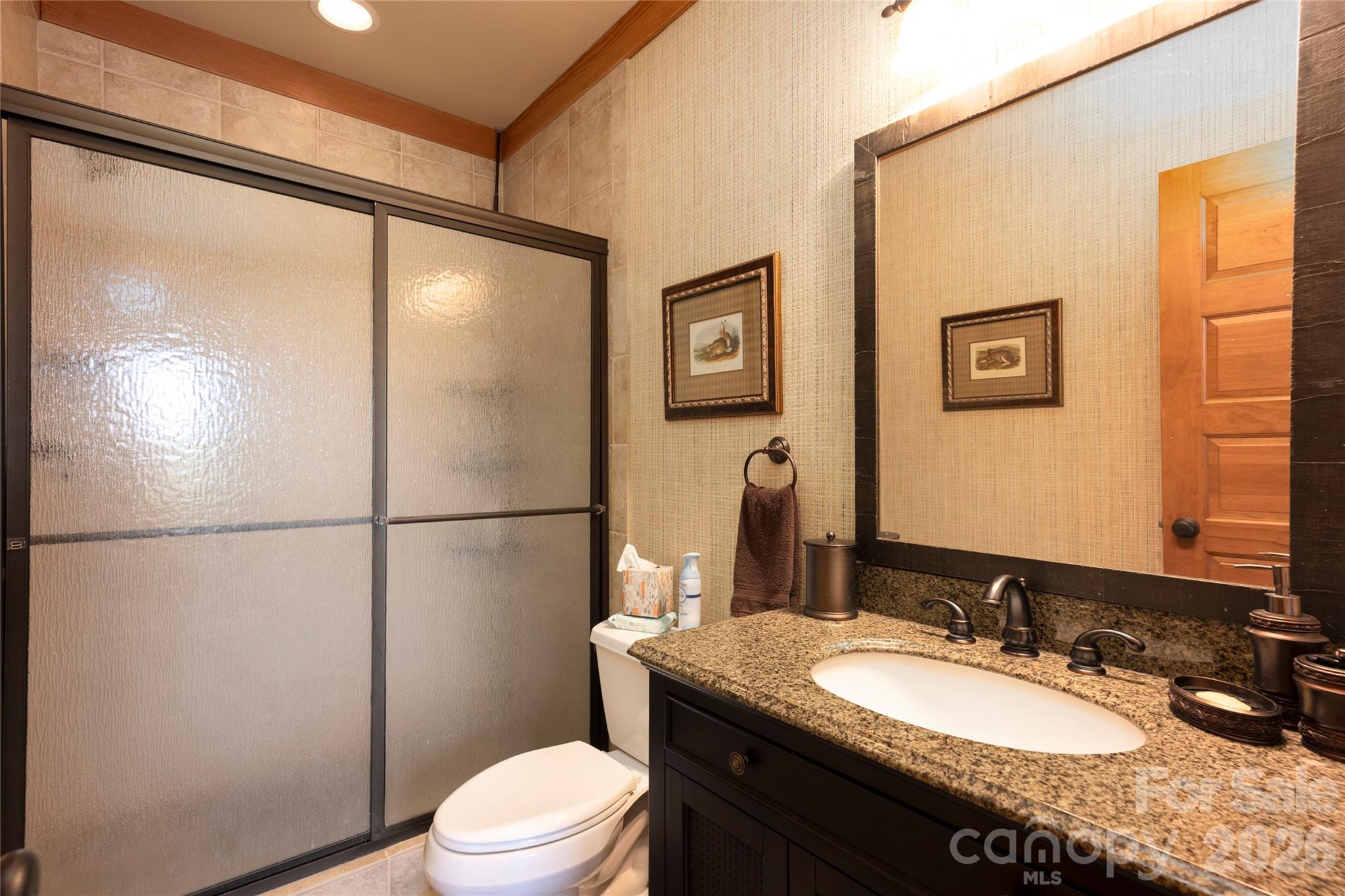 601 Hawk Mountain Road Lake Toxaway, NC 28747 - Photo 36 of 48 a bathroom with a granite countertop sink toilet a mirror and a shower
