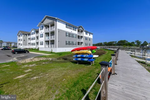 a front view of a building with a garden and trees