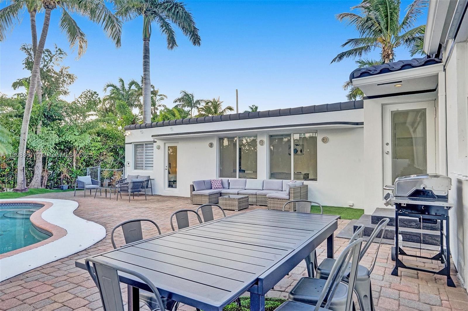 725 Harrison Street Hollywood, FL 33019 - Photo 77 of 91 a view of a patio with table and chairs with wooden floor and fence
