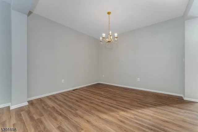 a view of empty room with wooden floor chandelier