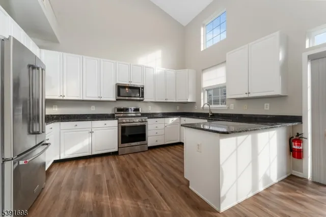a kitchen with granite countertop white cabinets and stainless steel appliances