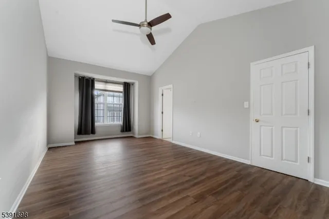 an empty room with wooden floor chandelier fan and windows
