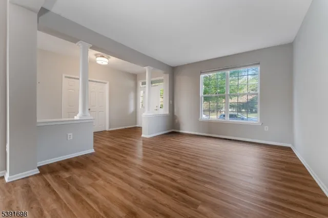 an empty room with wooden floor and windows
